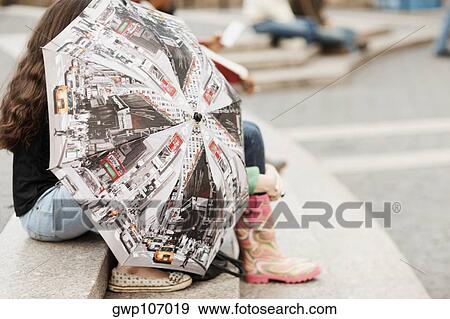 Stock Photo - Two women sitting on steps behind an umbrella. Fotosearch