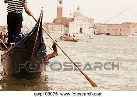 Mid section view of a gondolier sailing a gondola in a canal, Venice, Veneto, Italy View Large Photo Image Stock Photography - Mid section view of a gondolier sailing a gondola in a canal, Venice, Veneto, Italy. Fotosearch
