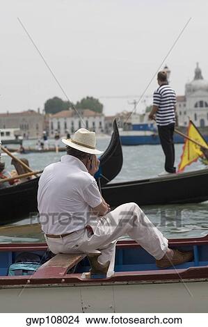 Rear view of a man sitting in a gondola, and using a mobile phone, Venice, Veneto, Italy View Large Photo Image Picture - Rear view of a man sitting in a gondola, and using a mobile phone, Venice, Veneto, Italy. Fotosearch