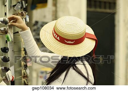 Side profile of a woman picking sunglasses from a market stall View Large Photo Image Picture - Side profile of a woman picking sunglasses from a market stall. Fotosearch