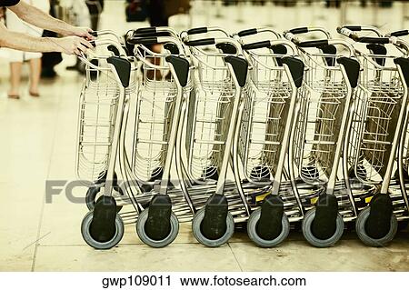 Close-up of human hands pushing a row of luggage carts at an airport, Madrid, Spain View Large Photo Image Stock Image - Close-up of human hands pushing a row of luggage carts at an airport, Madrid, Spain. Fotosearch