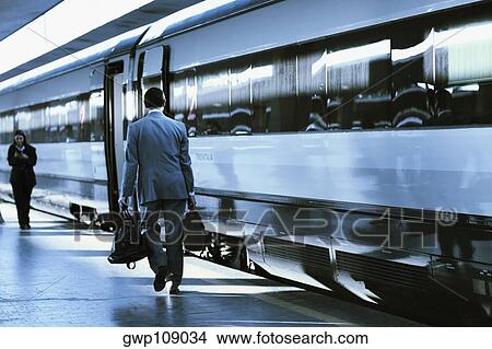 Rear view of a man and a woman walking at a railroad station, Rome, Italy View Large Photo Image Picture - Rear view of a man and a woman walking at a railroad station, Rome, Italy. Fotosearch