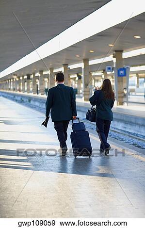 Rear view of a man and a woman walking at a railroad station, Rome, Italy View Large Photo Image Stock Photo - Rear view of a man and a woman walking at a railroad station, Rome, Italy. Fotosearch