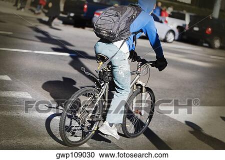 Rear view of a man cycling View Large Photo Image Stock Image - Rear view of a man cycling. Fotosearch