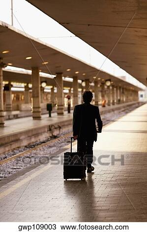 Rear view of a man pulling luggage at a railroad station platform, Rome, Italy View Large Photo Image Stock Image - Rear view of a man pulling luggage at a railroad station platform, Rome, Italy. Fotosearch