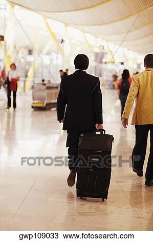 Rear view of a man walking and pulling luggage at an airport, Madrid, Spain View Large Photo Image Stock Image - Rear view of a man walking and pulling luggage at an airport, Madrid, Spain. Fotosearch