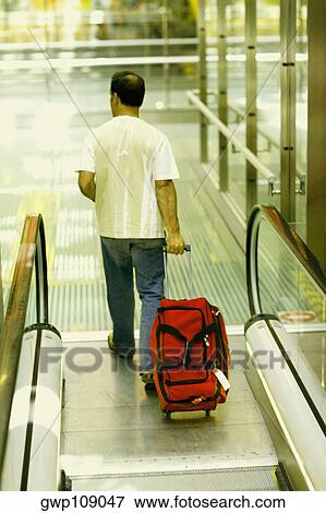 Rear view of a man walking and pulling luggage, Madrid, Spain View Large Photo Image Stock Photo - Rear view of a man walking and pulling luggage, Madrid, Spain. Fotosearch