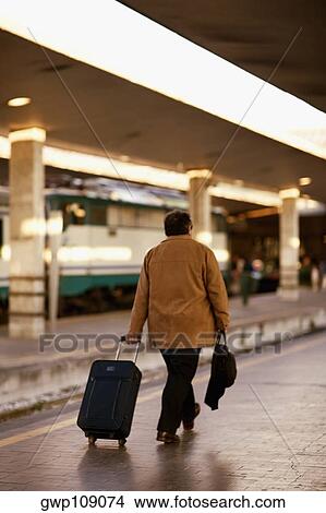 Rear view of a man walking at a railroad station platform, Rome, Italy View Large Photo Image Picture - Rear view of a man walking at a railroad station platform, Rome, Italy. Fotosearch