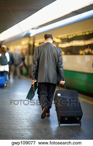 Rear view of a man walking at a railroad station platform, Rome, Italy View Large Photo Image Stock Photo - Rear view of a man walking at a railroad station platform, Rome, Italy. Fotosearch