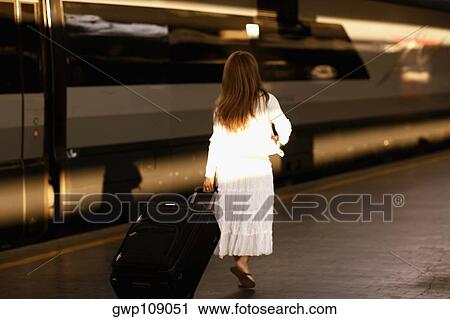 Rear view of a woman pulling her luggage at a railroad station platform, Rome, Italy View Large Photo Image Stock Image - Rear view of a woman pulling her luggage at a railroad station platform, Rome, Italy. Fotosearch