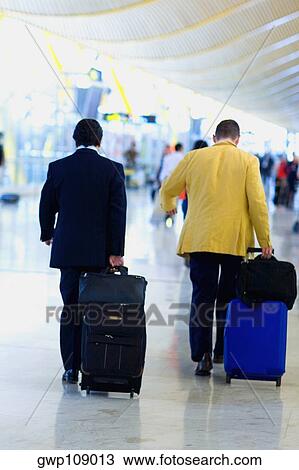 Rear view of two men walking and pulling luggage at an airport, Madrid, Spain View Large Photo Image Stock Image - Rear view of two men walking and pulling luggage at an airport, Madrid, Spain. Fotosearch