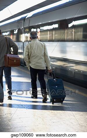 Rear view of two men walking at a railroad station, Rome, Italy View Large Photo Image Stock Image - Rear view of two men walking at a railroad station, Rome, Italy. Fotosearch