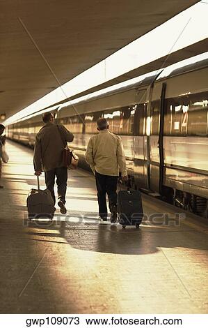 Rear view of two men walking at a railroad station, Rome, Italy View Large Photo Image Stock Image - Rear view of two men walking at a railroad station, Rome, Italy. Fotosearch