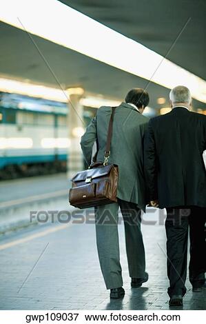 Rear view of two men walking at a railroad station platform, Rome, Italy View Large Photo Image Stock Photo - Rear view of two men walking at a railroad station platform, Rome, Italy. Fotosearch