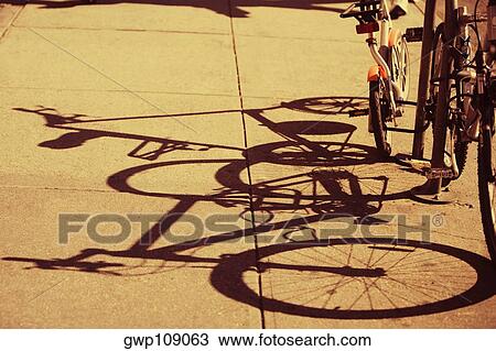 Stock Image - Shadow of bicycles on the sidewalk. Fotosearch