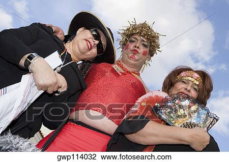 Stock Image - Low angle view of a mature man with two mature women wearing costumes. Fotosearch