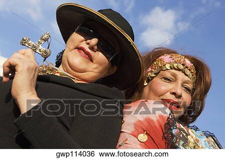 Low angle view of a mature woman holding a cross with another mature woman behind her View Large Photo Image Stock Photograph - Low angle view of a mature woman holding a cross with another mature woman behind her. Fotosearch