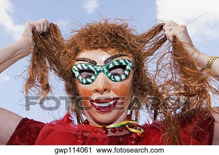 Low angle view of a woman wearing a carnival mask and holding her hair View Large Photo Image Stock Image - Low angle view of a woman wearing a carnival mask and holding her hair. Fotosearch