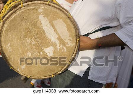 Mid section view of a man holding a drum View Large Photo Image Stock Photo - Mid section view of a man holding a drum. Fotosearch