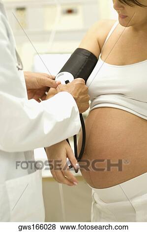 Stock Photo - Close-up of a male doctor checking pregnant young woman's blood pressure. Fotosearch