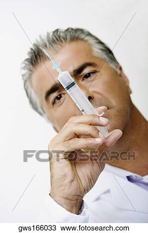 Stock Image - Close-up of a male doctor holding a syringe. Fotosearch
