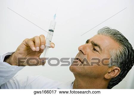 Close-up of a male doctor holding a syringe View Large Photo Image Stock Photo - Close-up of a male doctor holding a syringe. Fotosearch