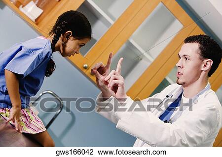 Stock Image - Girl sitting on a table in front of a male doctor. Fotosearch