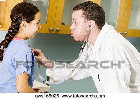 Male doctor examining a girl with a stethoscope View Large Photo Image Stock Photography - Male doctor examining a girl with a stethoscope. Fotosearch