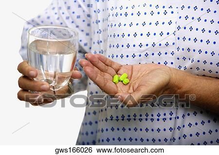 Mid section view of a woman holding a glass of water and pills View Large Photo Image Stock Photograph - Mid section view of a woman holding a glass of water and pills. Fotosearch
