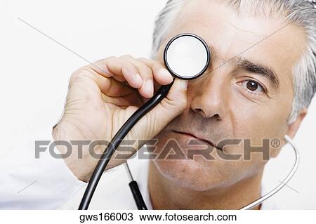 Portrait of a male doctor holding a stethoscope in front of his eyes View Large Photo Image Stock Image - Portrait of a male doctor holding a stethoscope in front of his eyes. Fotosearch