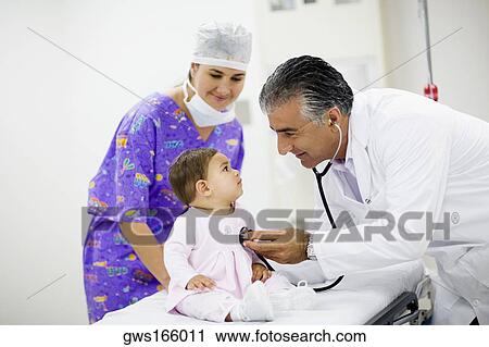 Side profile of a male doctor examining a baby girl with a stethoscope and a female doctor standing near them View Large Photo Image Stock Image - Side profile of a male doctor examining a baby girl with a stethoscope and a female doctor standing near them. Fotosearch