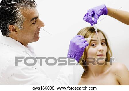 Side profile of a male doctor injecting a female patient View Large Photo Image Stock Photo - Side profile of a male doctor injecting a female patient. Fotosearch