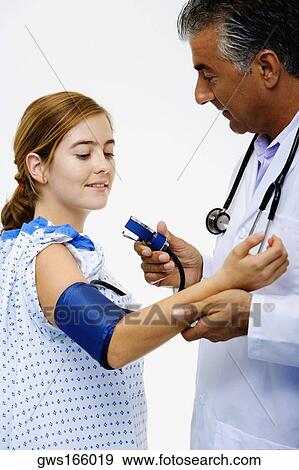 Stock Photo - Side profile of a male doctor measuring blood pressure of a young woman. Fotosearch