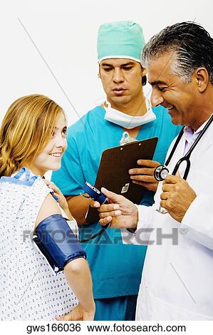 Side profile of a male doctor measuring blood pressure of a young woman View Large Photo Image Stock Photograph - Side profile of a male doctor measuring blood pressure of a young woman. Fotosearch