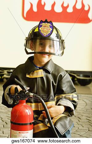 Picture - Close-up of a boy dressed as a firefighter and holding a fire extinguisher. Fotosearch