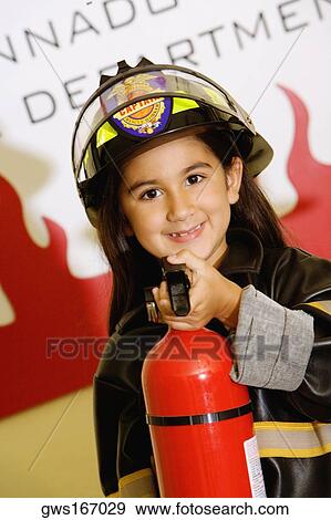 Close-up of a girl dressed as a firefighter and holding a fire extinguisher View Large Photo Image Stock Photo - Close-up of a girl dressed as a firefighter and holding a fire extinguisher. Fotosearch