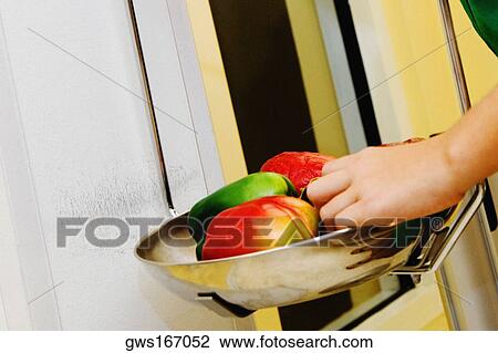 Stock Image - Close-up of a girl weighing vegetables in a weight scale. Fotosearch