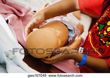 Stock Photo - Close-up of child's hands holding a doll. Fotosearch