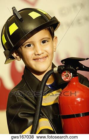 Stock Photo - Portrait of a boy dressed as a firefighter and holding a fire extinguisher. Fotosearch