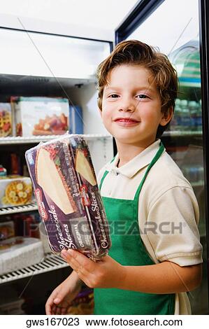 Stock Image - Portrait of a boy holding a box of cake and smiling. Fotosearch