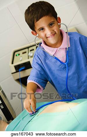 Stock Image - Portrait of a boy imitating a doctor and examining a patient with a stethoscope. Fotosearch