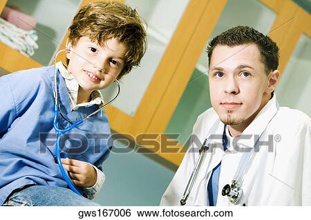 Portrait of a boy listening to his heartbeats with a stethoscope and a male doctor beside him View Large Photo Image Stock Photograph - Portrait of a boy listening to his heartbeats with a stethoscope and a male doctor beside him. Fotosearch