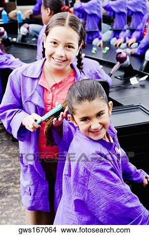 Portrait of a girl combing her sister's hair in a salon View Large Photo Image Picture - Portrait of a girl combing her sister's hair in a salon. Fotosearch