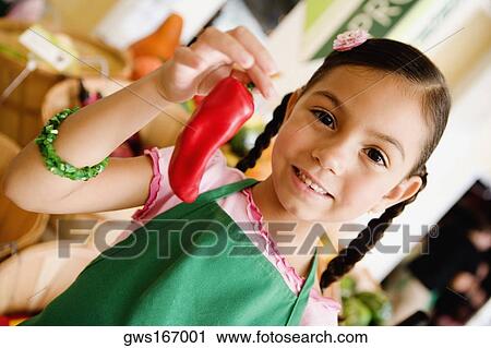 Stock Image - Portrait of a girl holding a red chili pepper. Fotosearch