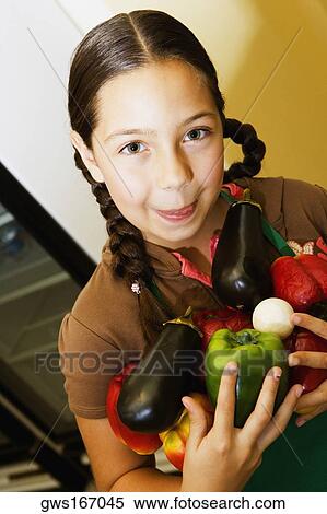 Stock Photography - Portrait of a girl holding vegetables. Fotosearch