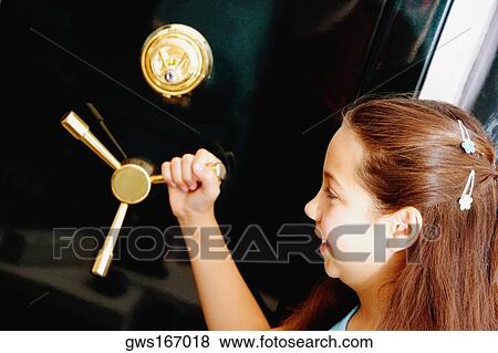 Stock Photo - Side profile of a girl holding the handle of a safe. Fotosearch