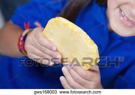 Close-up of a girl holding a slice of pineapple View Large Photo Image Stock Image - Close-up of a girl holding a slice of pineapple. Fotosearch
