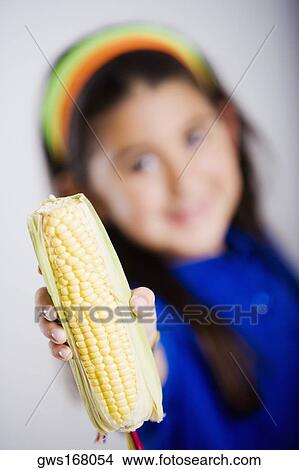 Close-up of a girl showing a corn cob View Large Photo Image Picture - Close-up of a girl showing a corn cob. Fotosearch