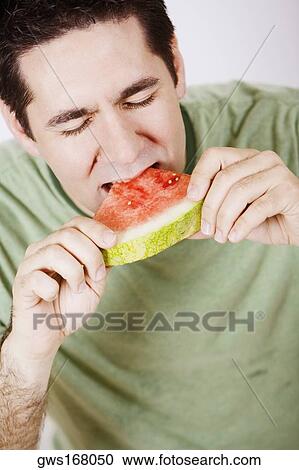 Close-up of a mid adult man eating a slice of watermelon View Large Photo Image Stock Image - Close-up of a mid adult man eating a slice of watermelon. Fotosearch
