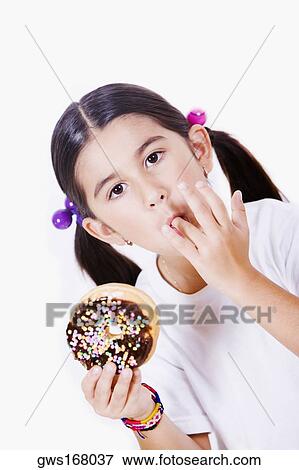 Portrait of a girl holding a donut and licking her finger View Large Photo Image Stock Photo - Portrait of a girl holding a donut and licking her finger. Fotosearch